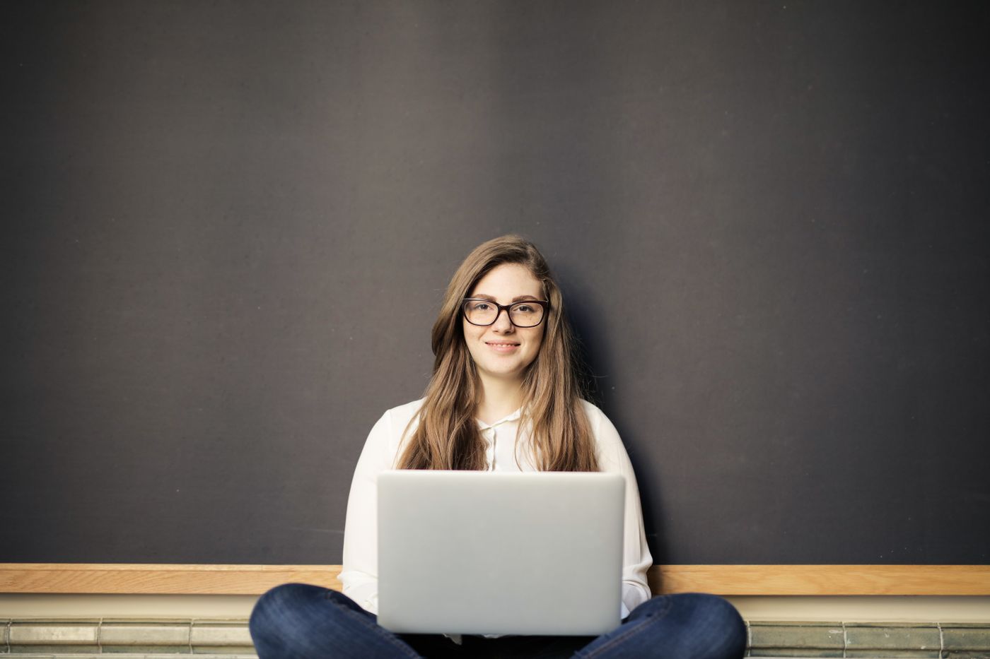 Mulher de óculos sorrindo enquanto trabalha no notebook