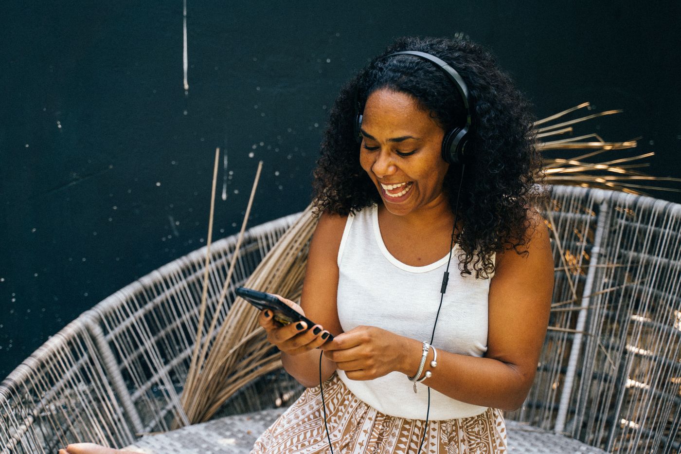 Mulher sorrindo com fones de ouvido e celular